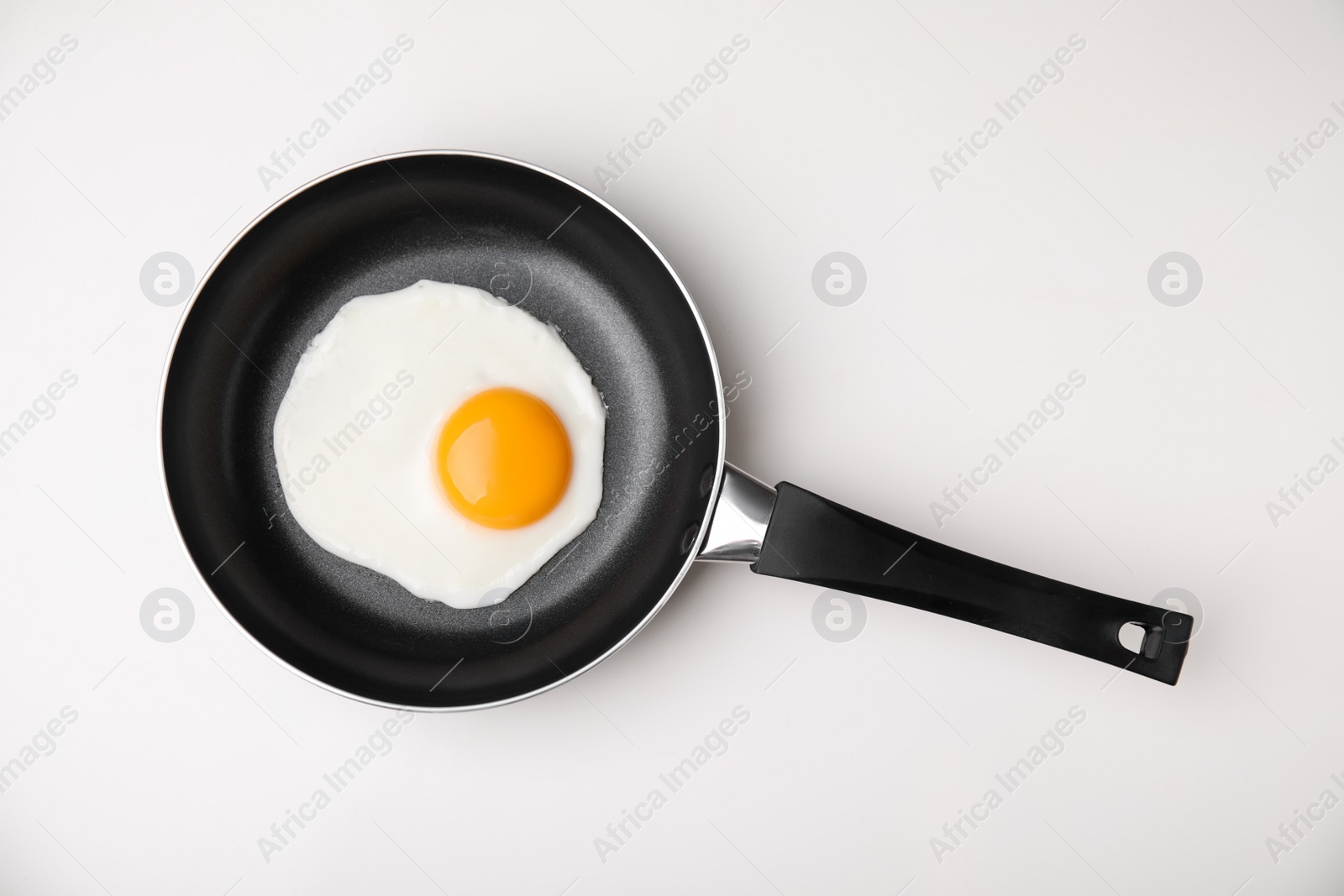 Photo of Tasty fried egg in pan on white background, top view