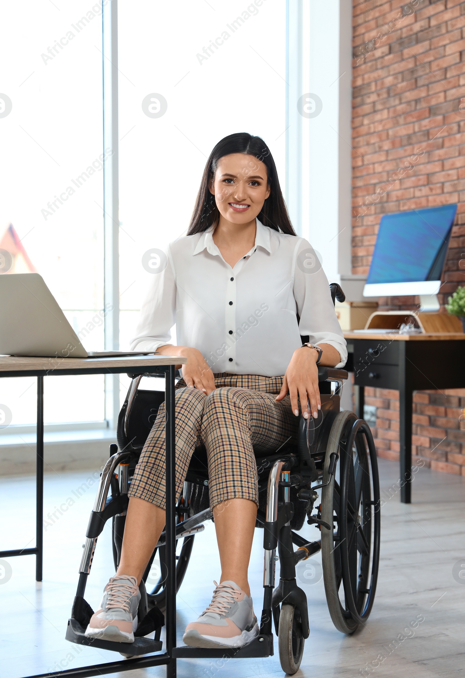 Photo of Portrait of young woman in wheelchair at workplace
