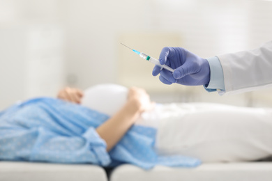 Photo of Doctor with syringe near pregnant woman in hospital, closeup. Vaccination concept