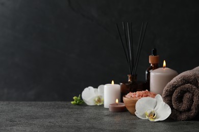 Beautiful composition with burning candles and different spa products on dark grey table. Space for text