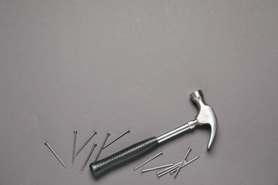 Hammer and metal nails on grey background, top view. Space for text