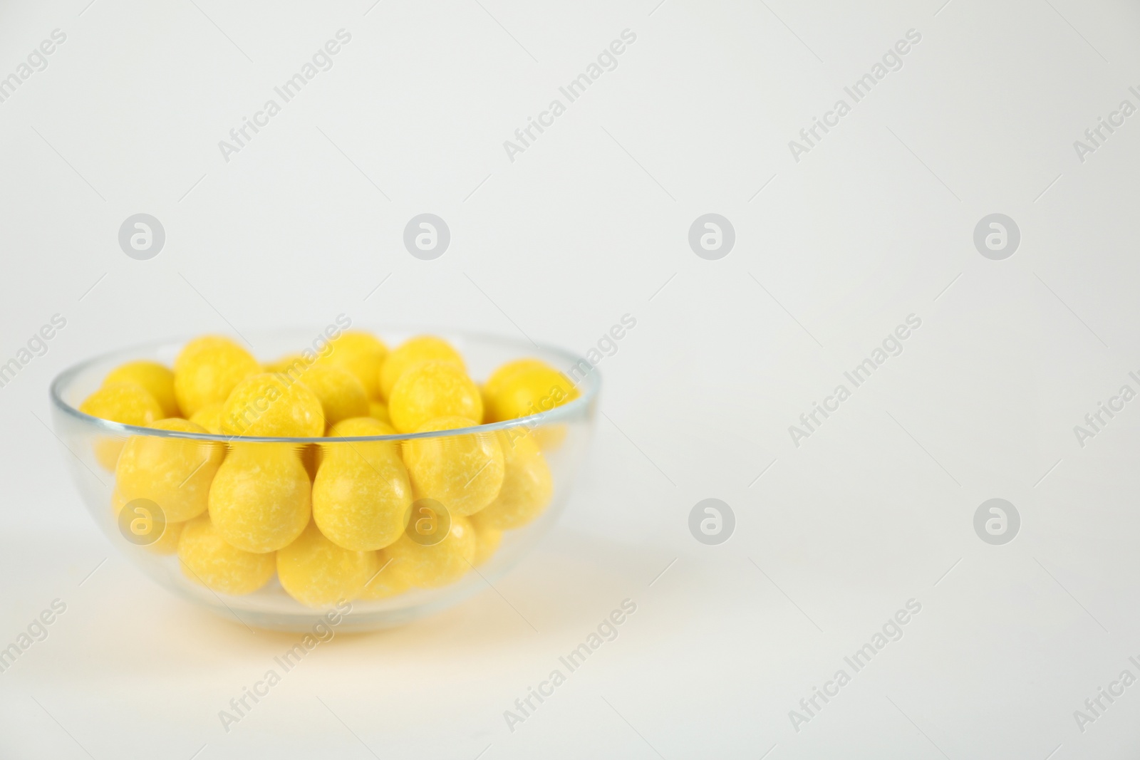 Photo of Tasty small lemon drops on white background