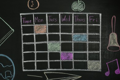 Photo of Weekly school timetable drawn with colorful chalk on blackboard