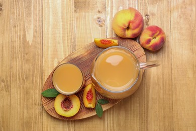 Delicious peach juice, fresh fruits and leaves on wooden table, flat lay