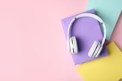 Photo of Modern headphones with hardcover books on color background, top view. Space for text
