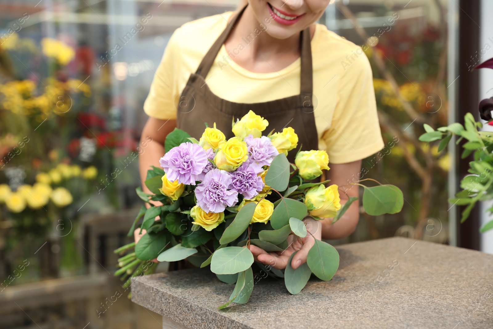 Photo of Female florist making beautiful bouquet in flower shop, closeup