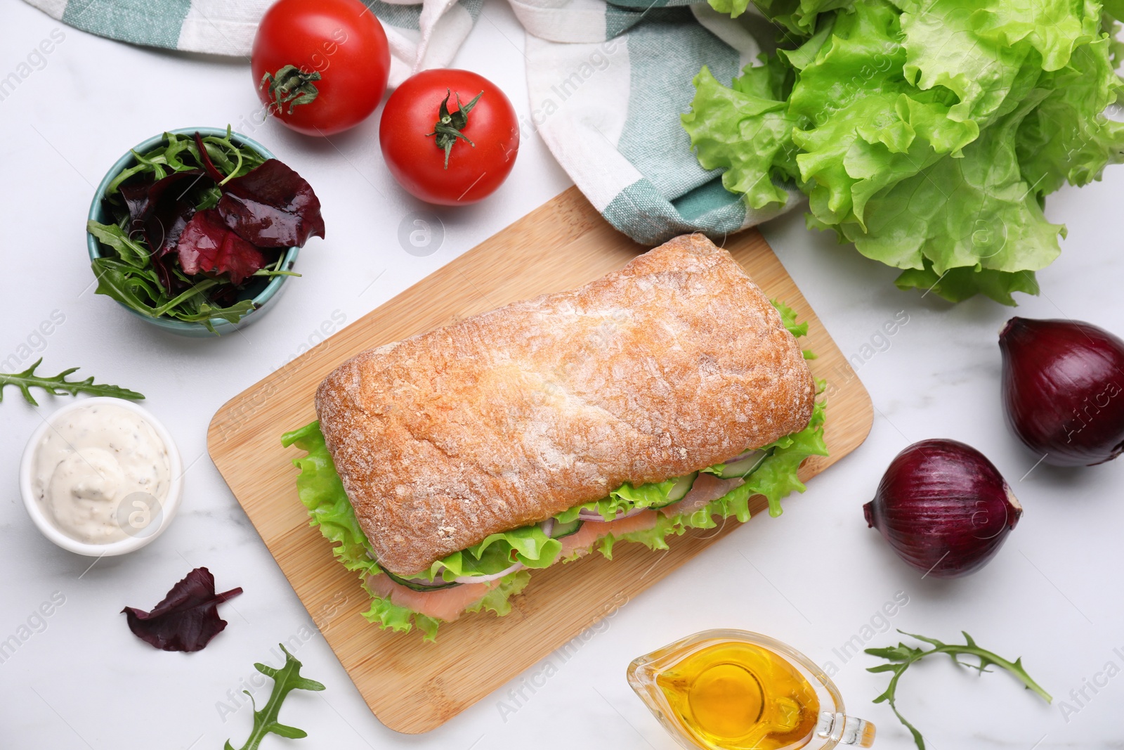 Photo of Delicious sandwich with salmon and ingredients on white table, flat lay