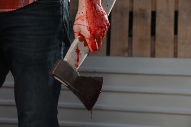 Photo of Man holding bloody axe outdoors, closeup. Space for text