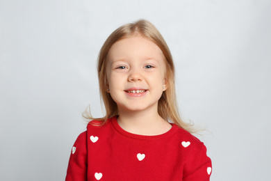 Portrait of cute little girl on light grey background