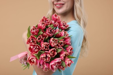 Photo of Happy woman with beautiful bouquet on beige background, closeup