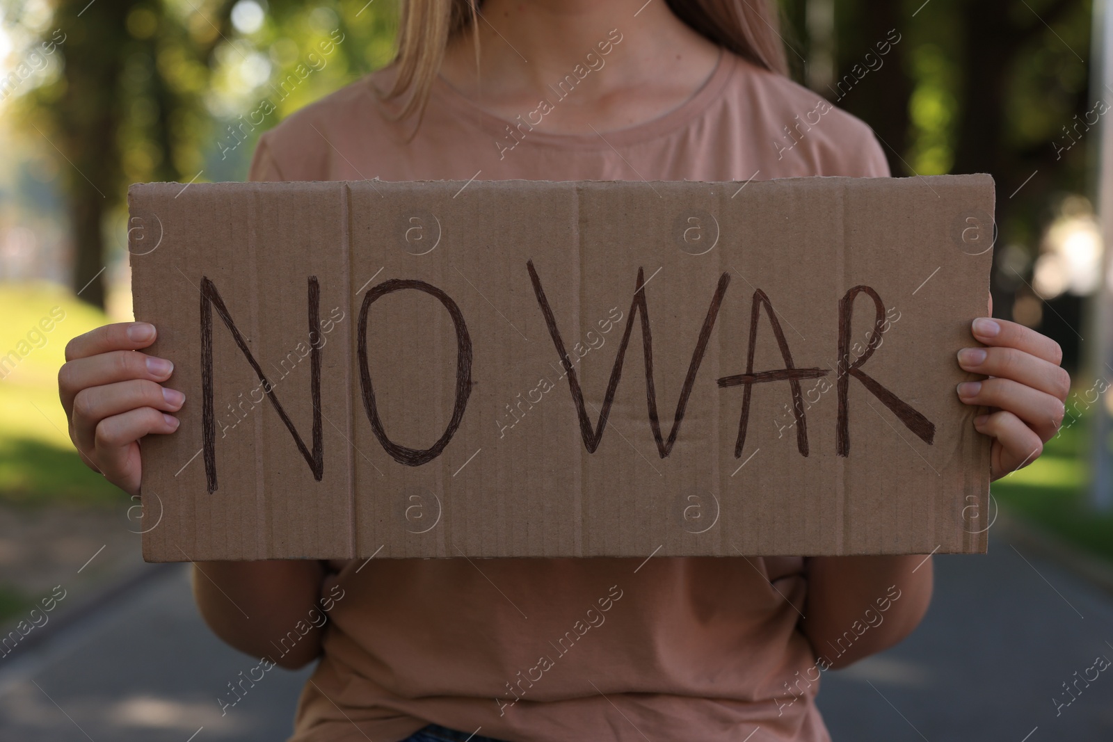 Photo of Woman holding poster with words No War in park, closeup