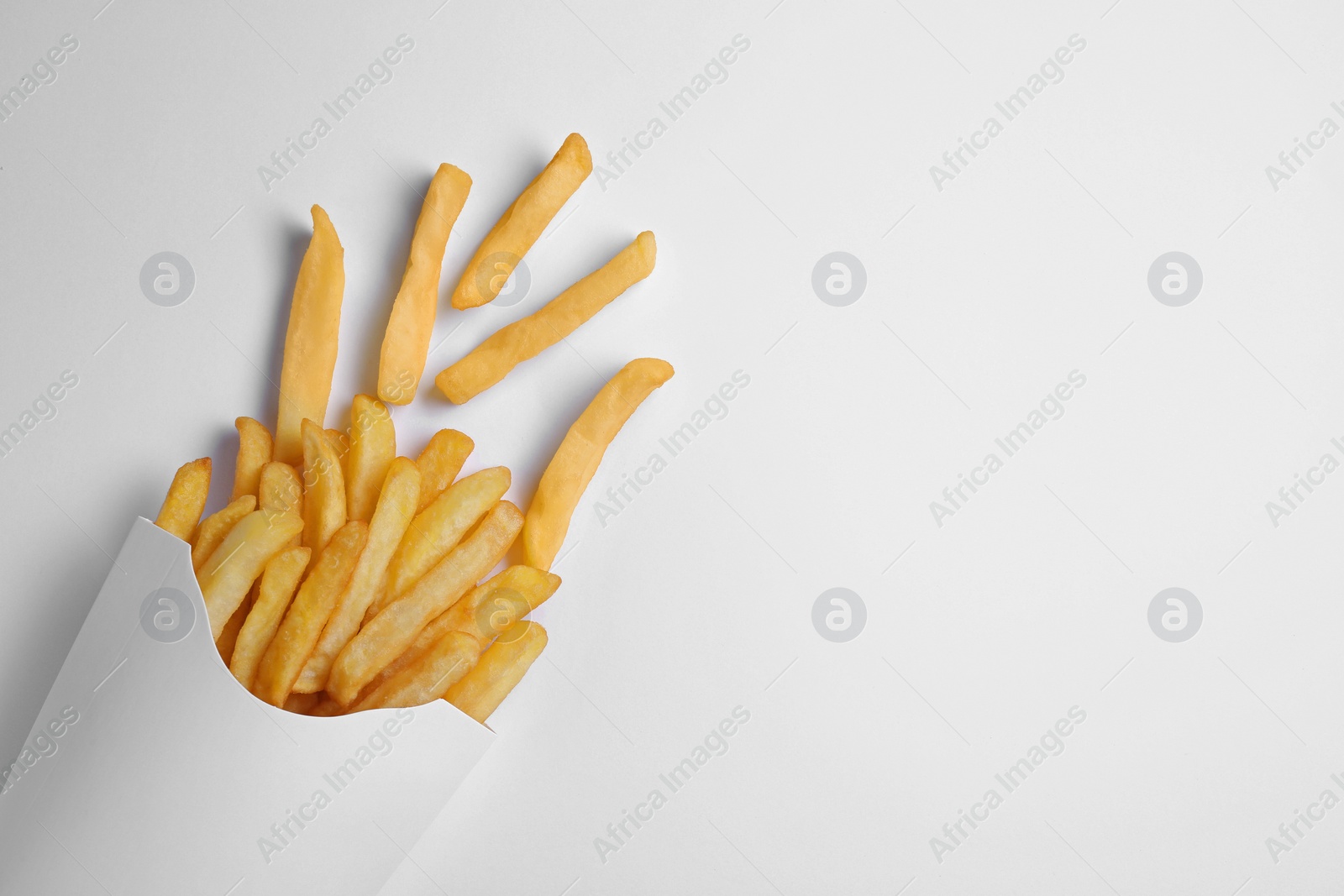 Photo of Paper cup with French fries on white table, flat lay. Space for text