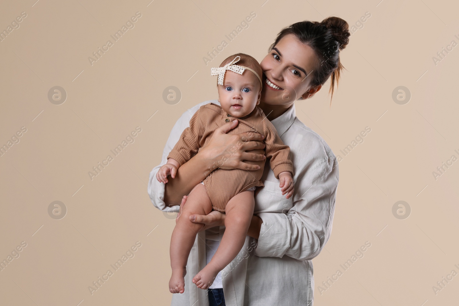 Photo of Beautiful mother with her cute baby on beige background