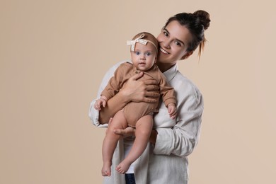 Beautiful mother with her cute baby on beige background