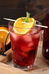 Photo of Glass of delicious refreshing sangria on wooden tray, closeup