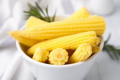 Photo of Tasty fresh yellow baby corns in bowl on white table, closeup