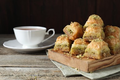 Photo of Delicious fresh baklava with chopped nuts on wooden table, closeup and space for text Eastern sweets