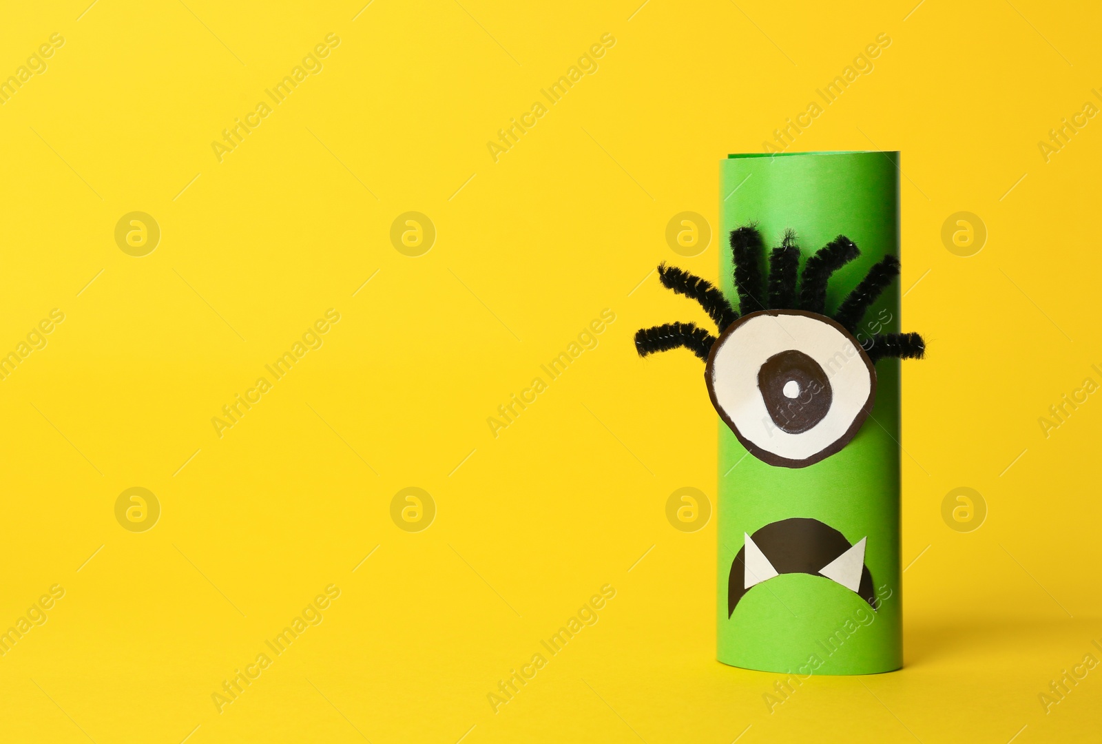 Photo of Funny green monster on yellow background, space for text. Halloween decoration