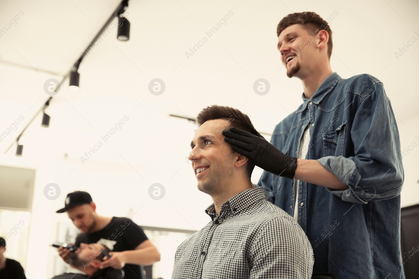 Photo of Professional barber working with client in hairdressing salon. Hipster fashion