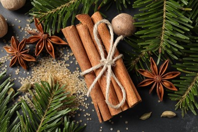 Different spices, nuts and fir branches on gray table, flat lay