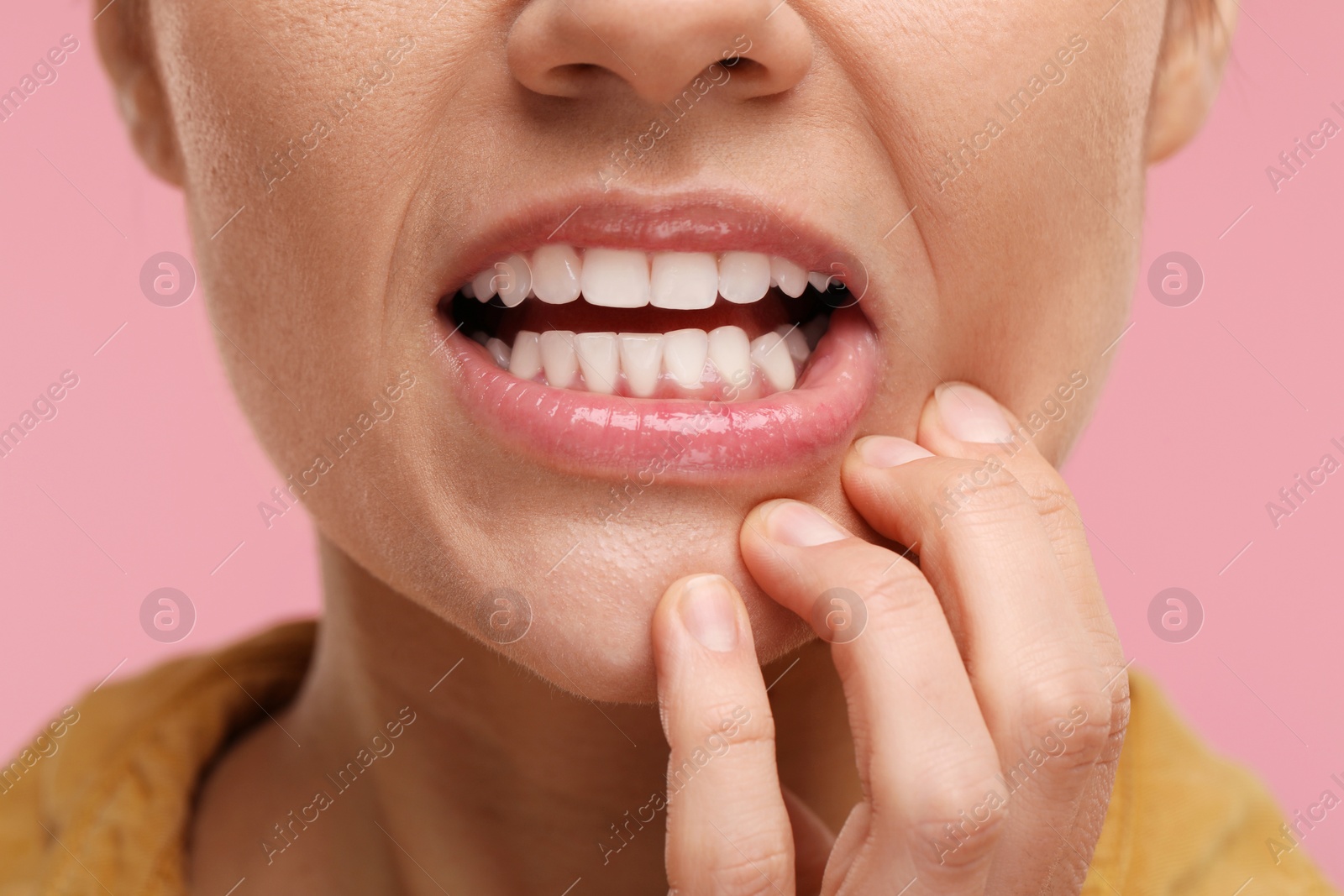 Photo of Woman showing her clean teeth on pink background, closeup