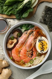 Photo of Delicious ramen with shrimps and egg in bowl served on table, flat lay. Noodle soup