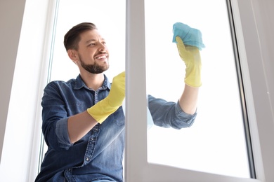 Man in casual clothes washing window glass at home