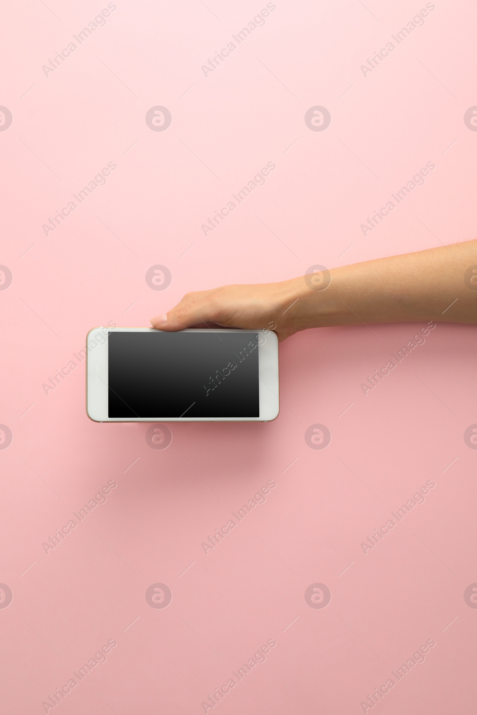 Photo of Woman holding modern phone on pink background, top view. Space for text