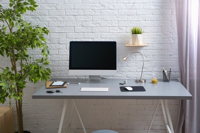 Photo of Interior of comfortable work place with computer on table at home