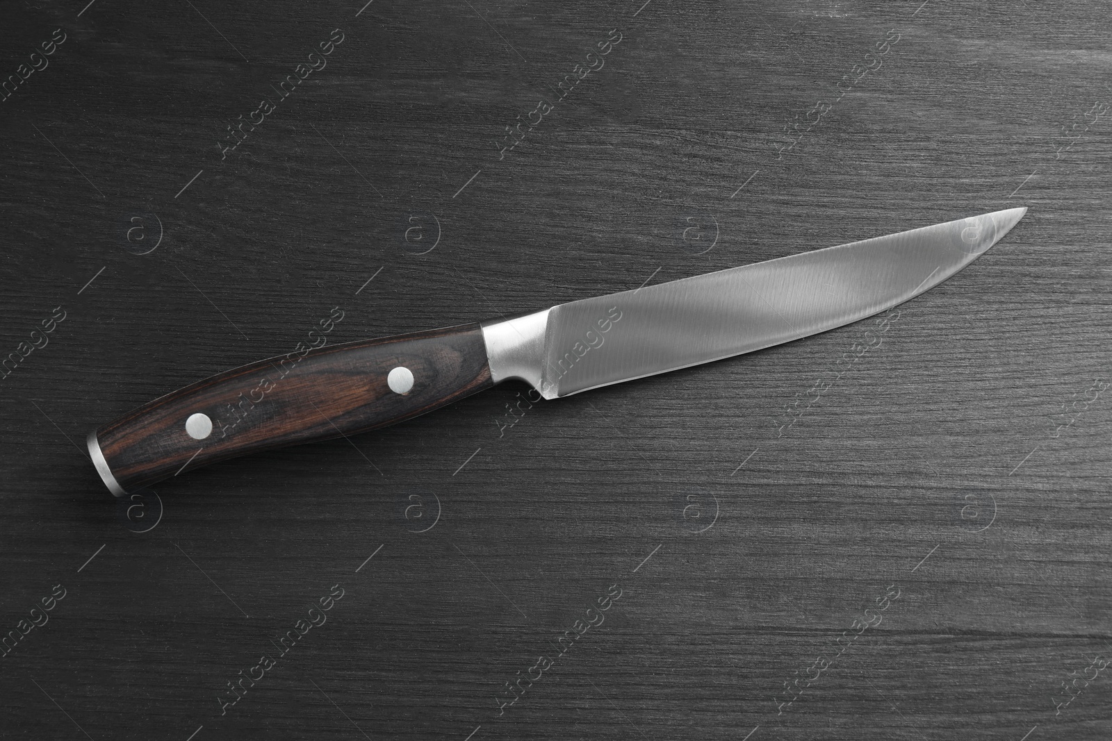 Photo of One sharp knife on black wooden table, top view