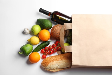 Photo of Paper bag with different groceries on white background, top view