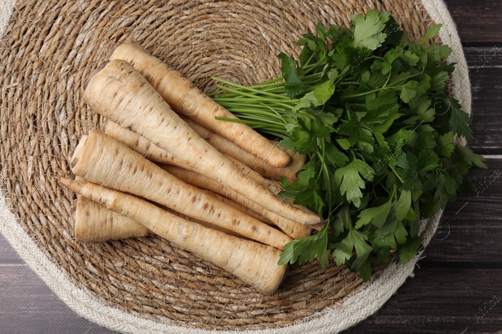 Photo of Raw parsley roots and bunch of fresh herb on wooden table, flat lay