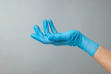 Photo of Doctor wearing light blue medical glove holding something on grey background, closeup