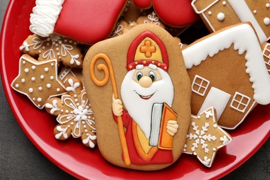 Photo of Tasty gingerbread cookies on red plate, top view. St. Nicholas Day celebration