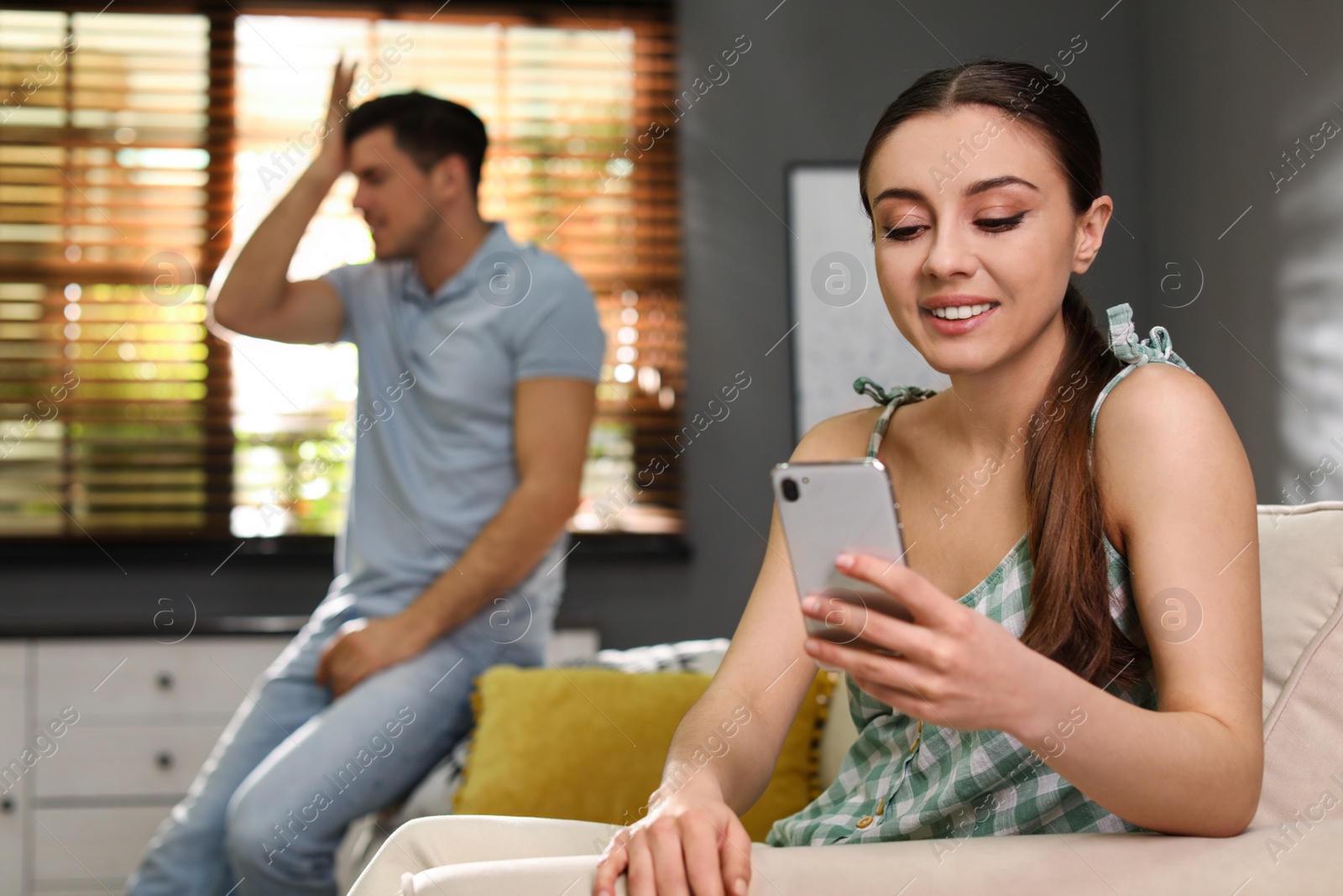 Photo of Woman preferring smartphone over spending time with her boyfriend at home. Jealousy in relationship