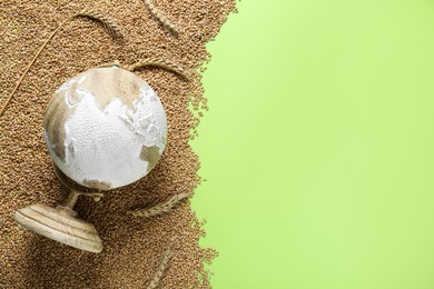 Photo of Globe and grains on light green background, top view. Hunger crisis concept