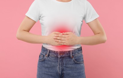 Woman suffering from stomach pain on pink background, closeup