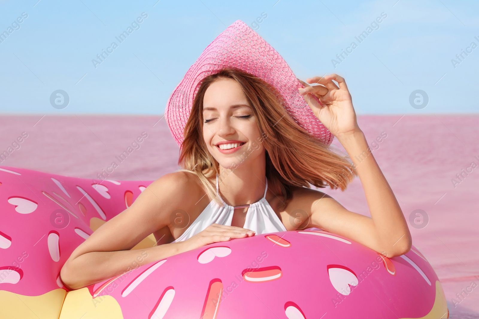 Photo of Beautiful woman with inflatable ring near pink lake