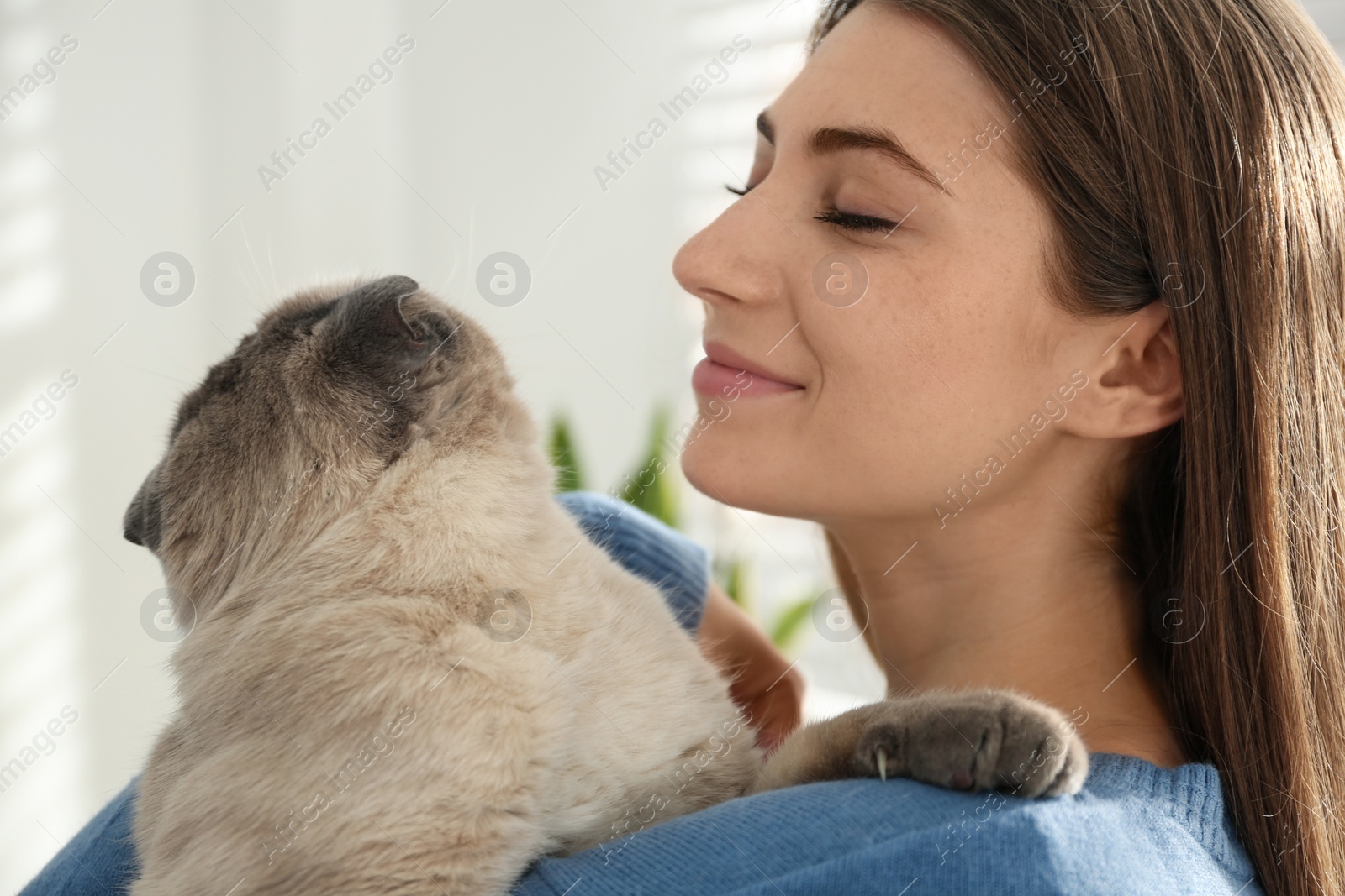 Photo of Young woman with cute cat at home, closeup. Fluffy pet