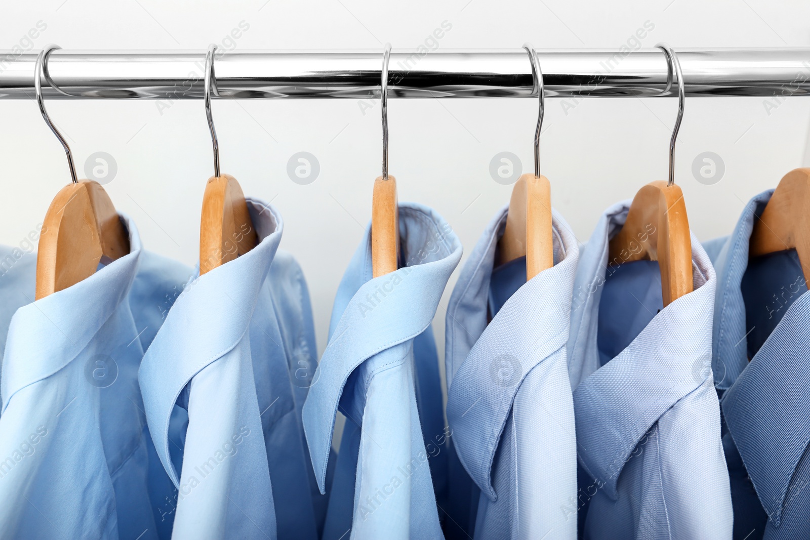 Photo of Rack with clean clothes after dry-cleaning on hangers