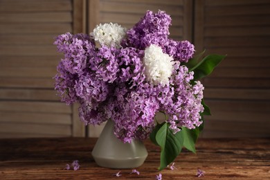 Photo of Beautiful lilac flowers in vase on wooden table