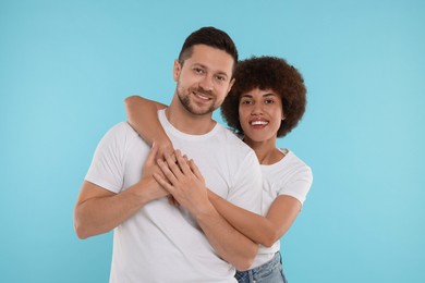 International dating. Happy couple hugging on light blue background
