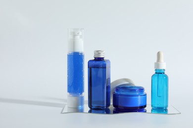 Different containers with cosmetic products on light background