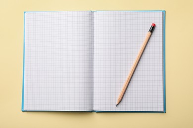Photo of Open notebook with blank sheets and pencil on beige background, top view