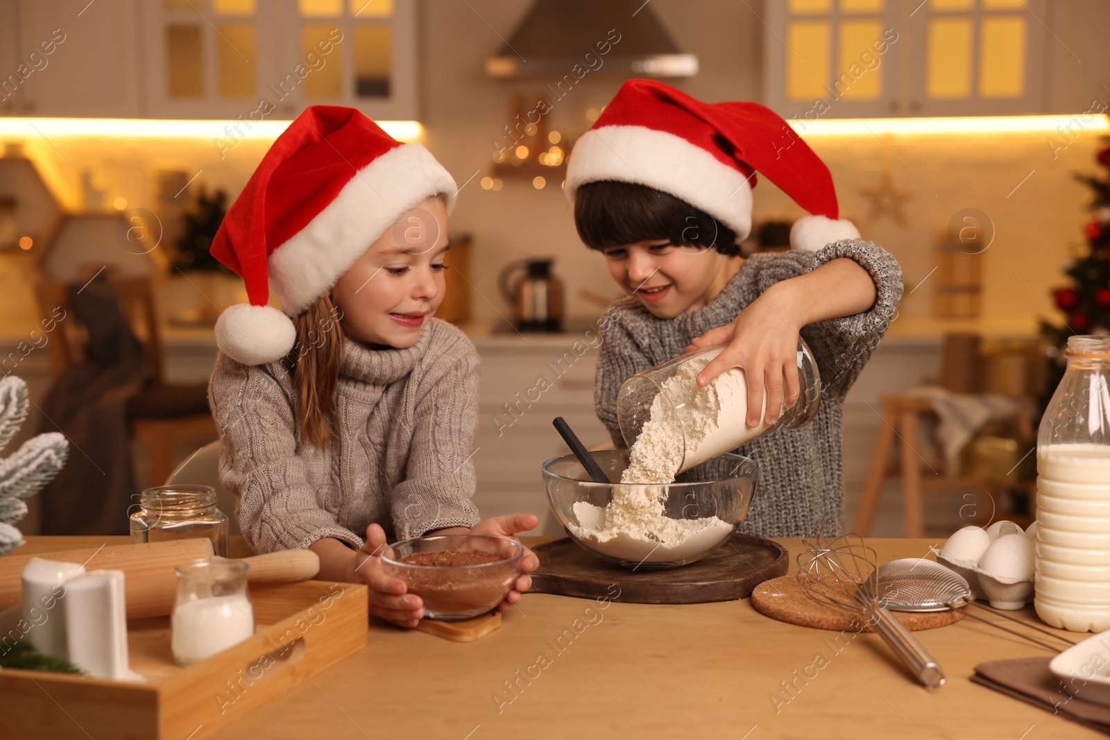 Photo of Cute little children making dough for Christmas cookies in kitchen