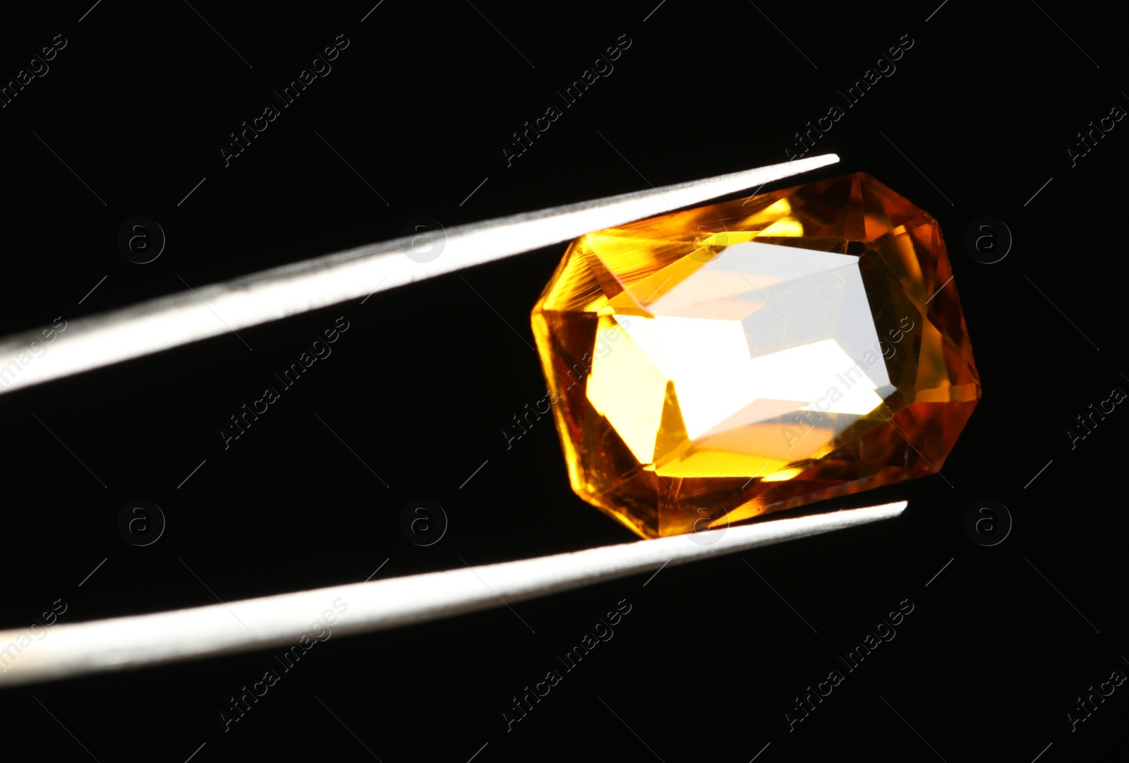 Photo of Tweezers with beautiful gemstone on black background