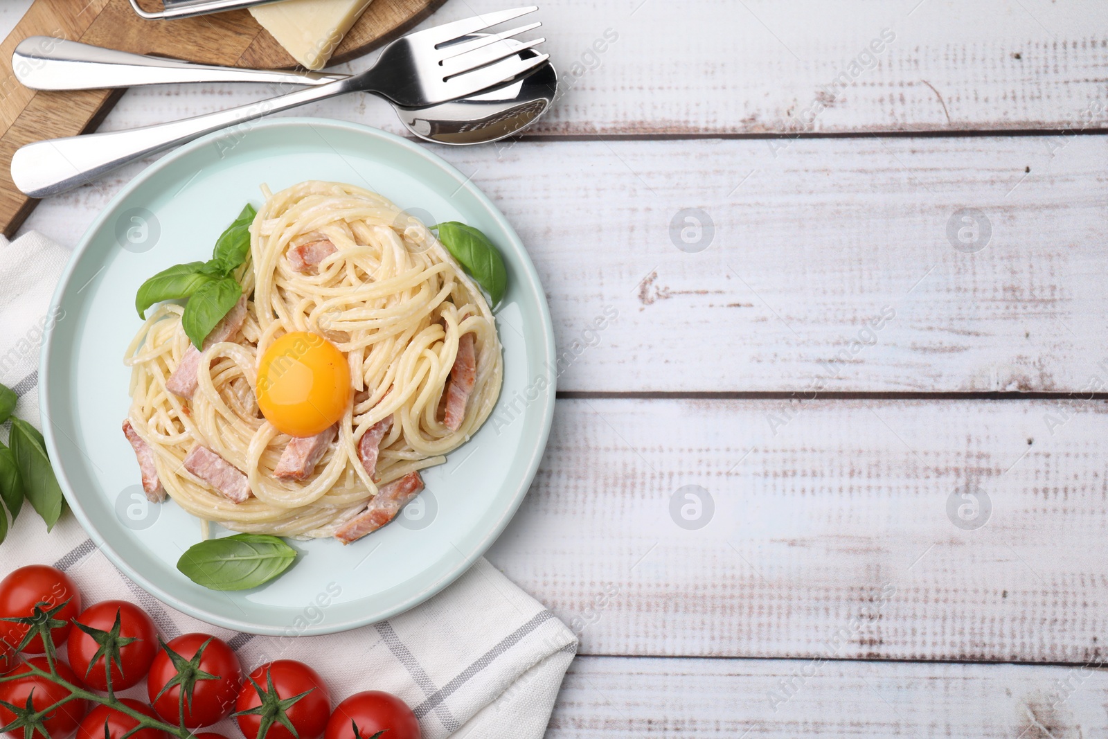 Photo of Delicious pasta Carbonara with egg yolk served on white wooden table, flat lay. Space for text