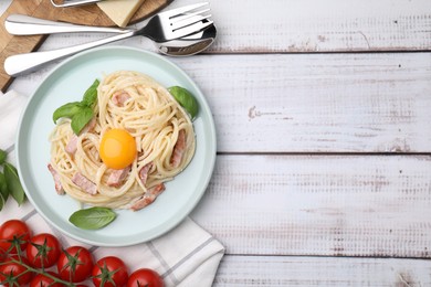 Photo of Delicious pasta Carbonara with egg yolk served on white wooden table, flat lay. Space for text