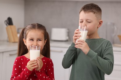 Photo of Cute children drinking fresh milk from glasses in kitchen