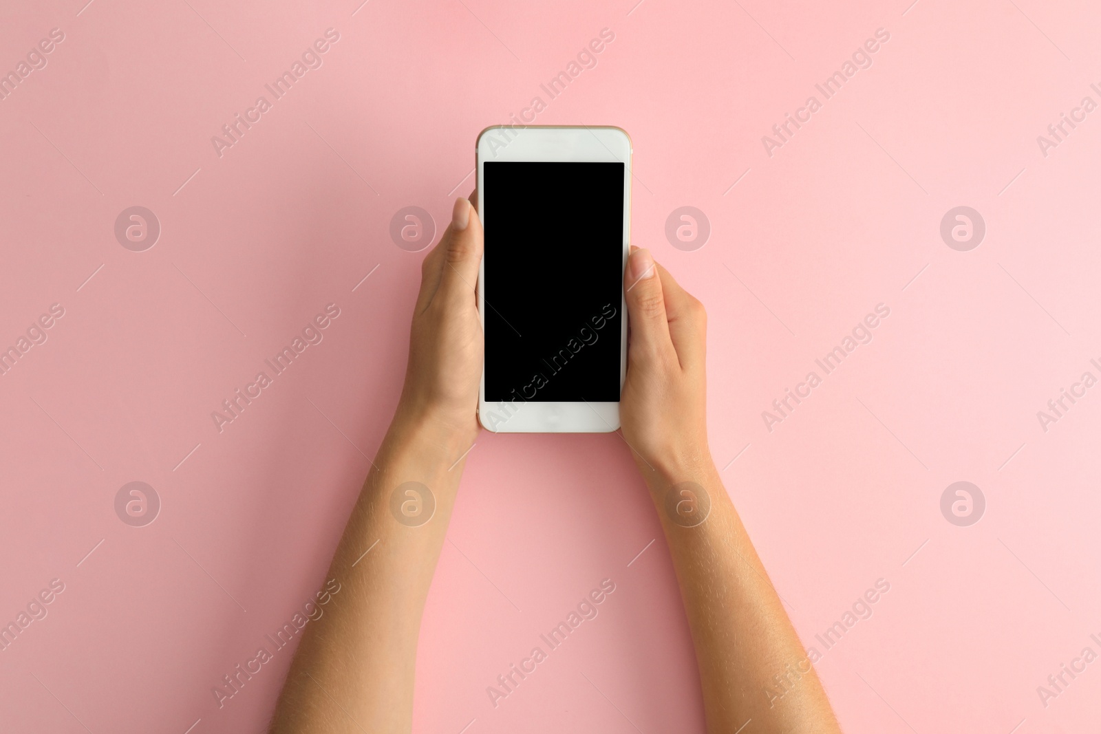 Photo of Woman holding modern phone on pink background, top view. Space for text